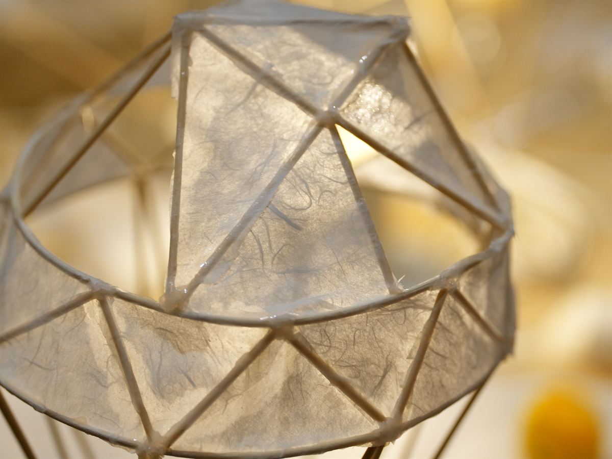 A finished paper lamp panel lit from inside with bamboo ribs visible through the paper.